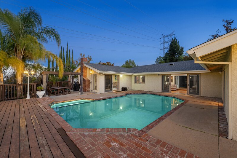 foto trasera de casa con alberca mediana al anochecer